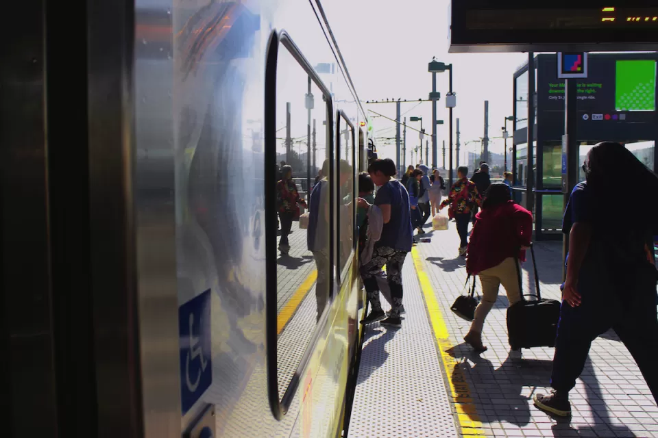People boarding Los Angeles Metro train on outdoor platform.